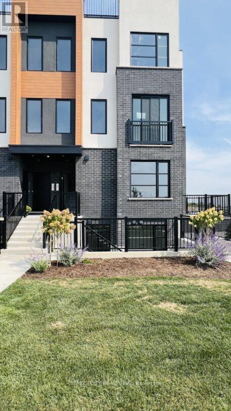 A modern building with a black fence and a small garden in front.
