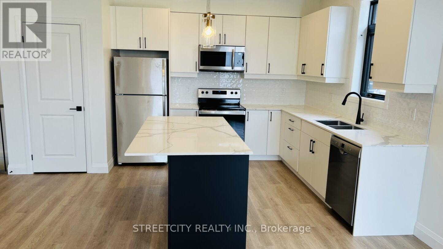 A kitchen with a refrigerator, microwave, oven, and sink.