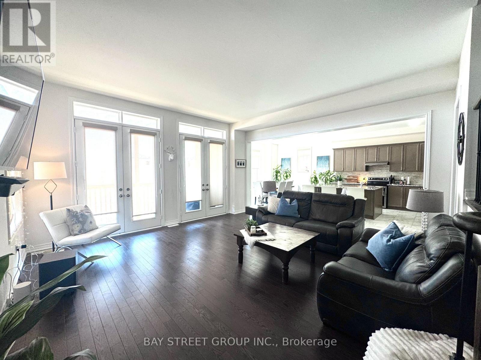 A living room with a black leather couch and a wooden floor.