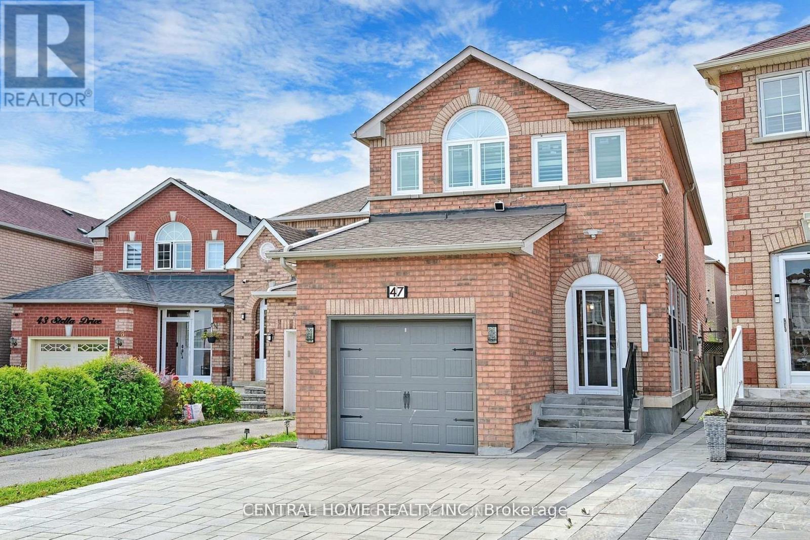 A red brick house with a grey garage door is for sale.
