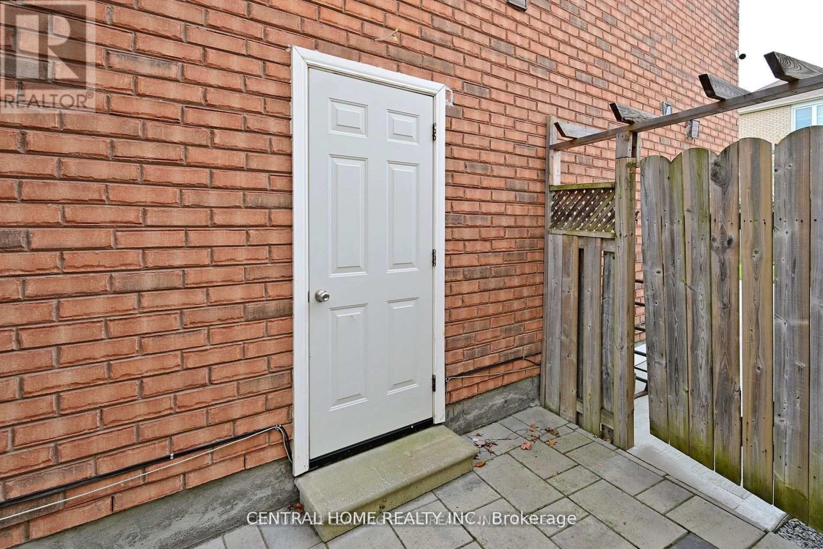 A white door is on the left side of a brick wall.