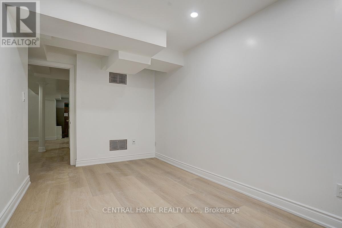 A spacious room with a white wall and wooden floor.