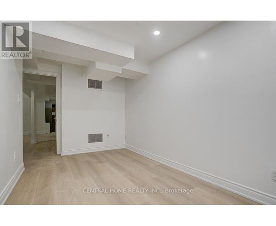 A spacious room with a white wall and wooden floor.