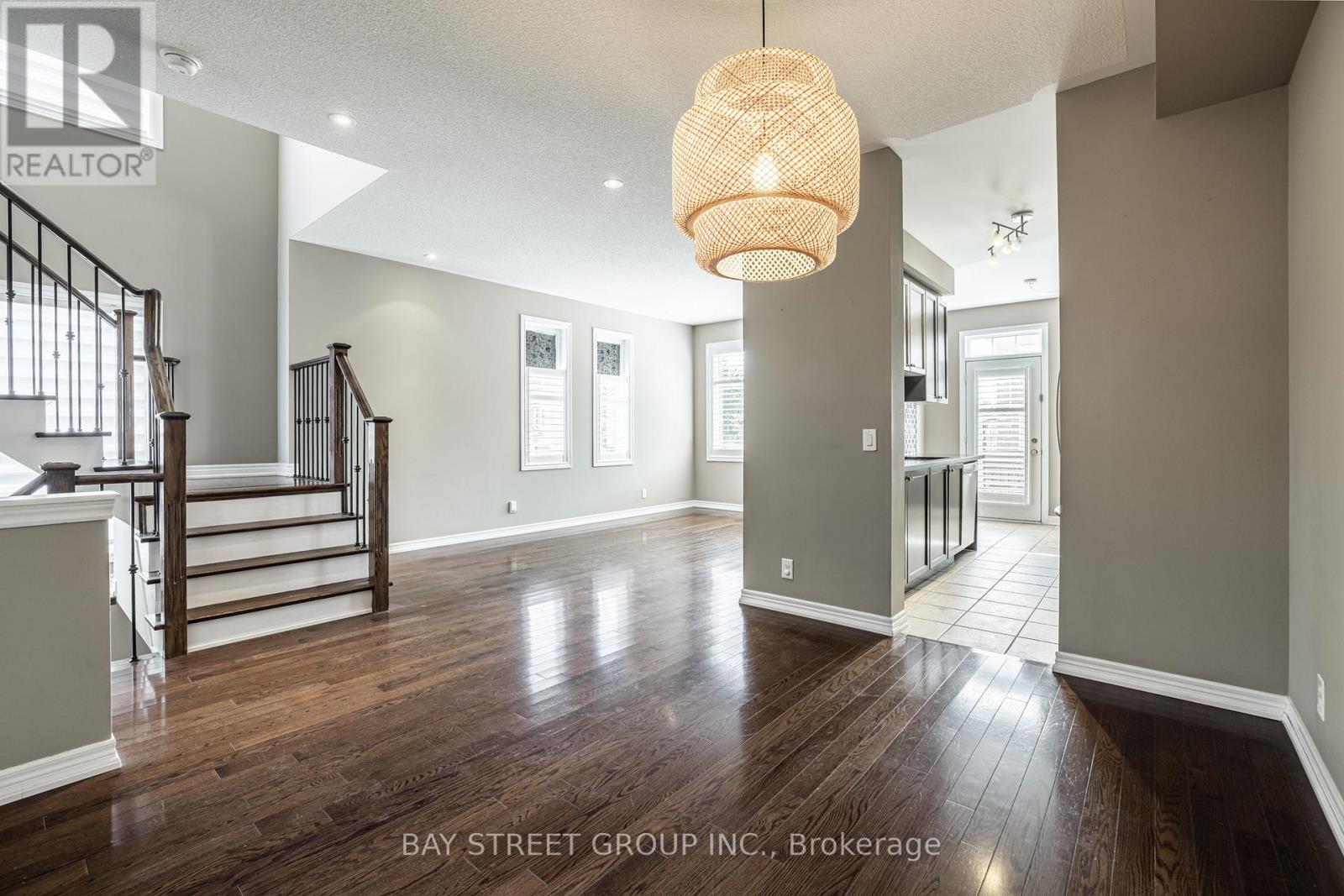 A spacious living room with wood flooring and a staircase.