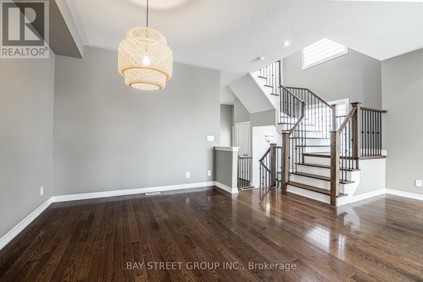 A spacious room with wooden floors and a staircase leading to another level.