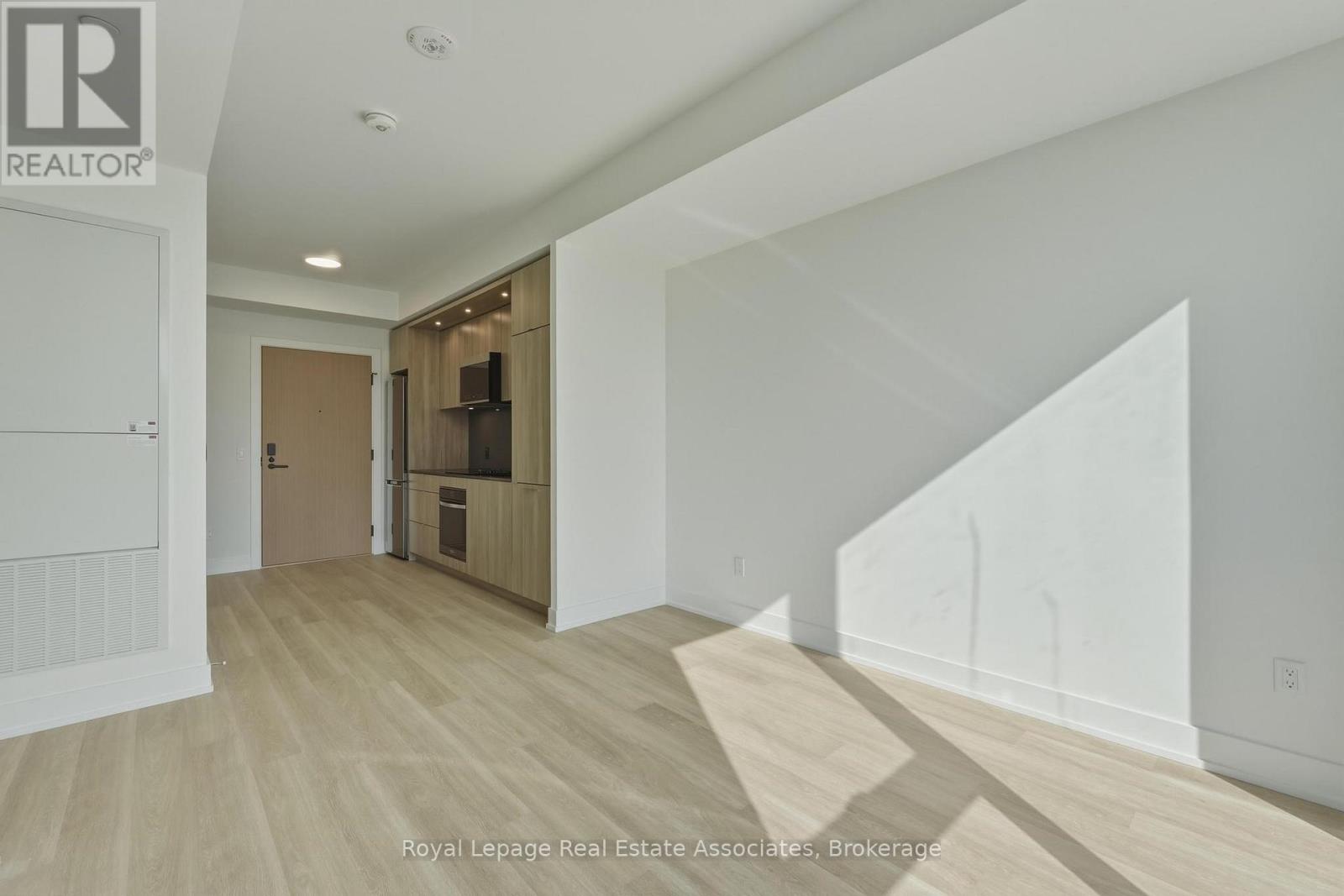 A spacious room with wooden flooring and white walls, with a door leading to another room.