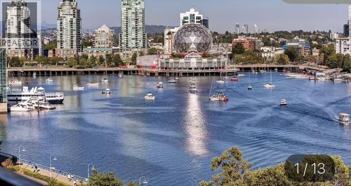 A cityscape with a large Ferris wheel in the background and boats in the water.