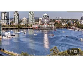 A cityscape with a large Ferris wheel in the background and boats in the water.