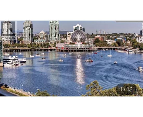 A cityscape with a large Ferris wheel in the background and boats in the water.