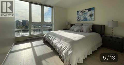 A bedroom with a large bed and a window overlooking a cityscape.