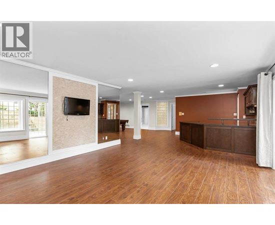 A spacious living room with wooden floors and a large television.