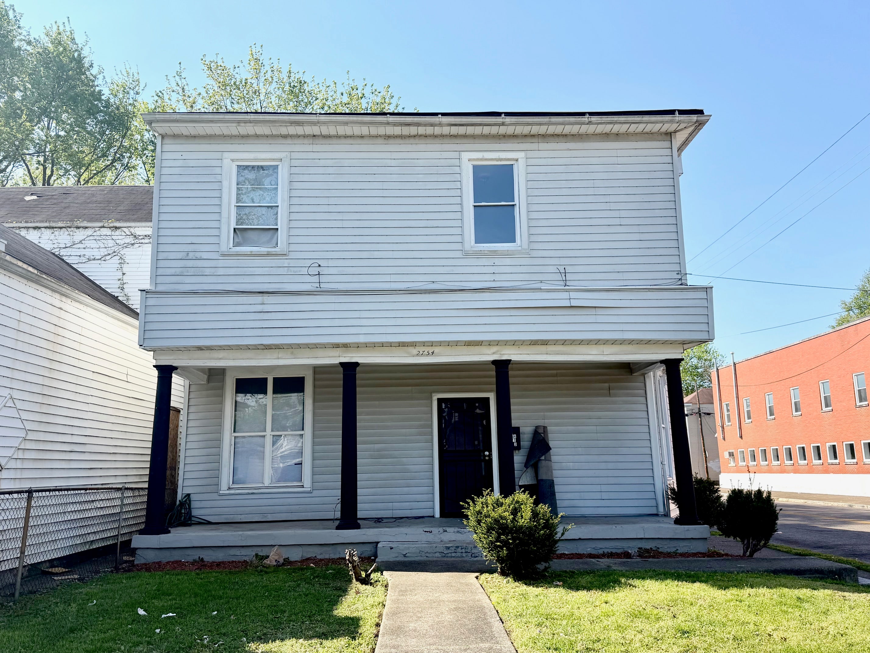 A two-story house with a front porch and a small front yard.