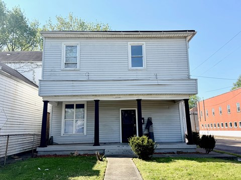 A two-story house with a front porch and a small front yard.
