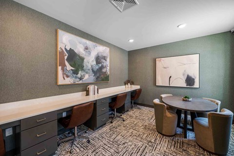 A conference room with a long table, chairs, and two paintings on the wall.