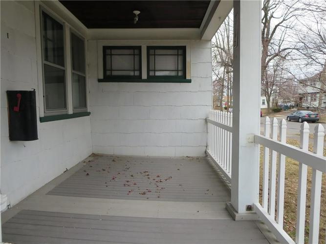 A white porch with a black speaker on the wall.