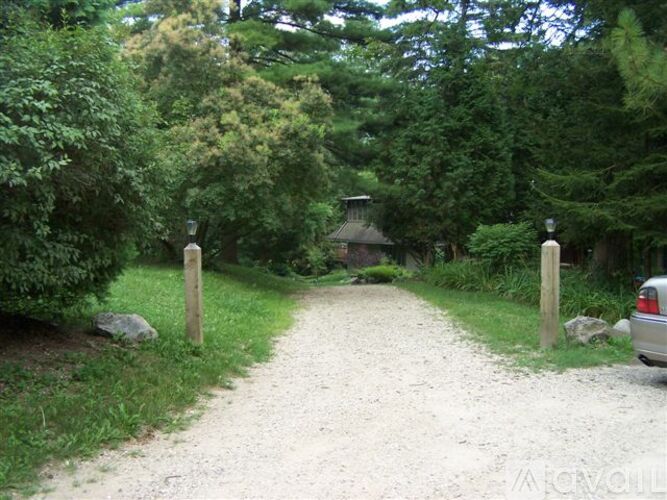 A gravel path leads to a small building in the woods.