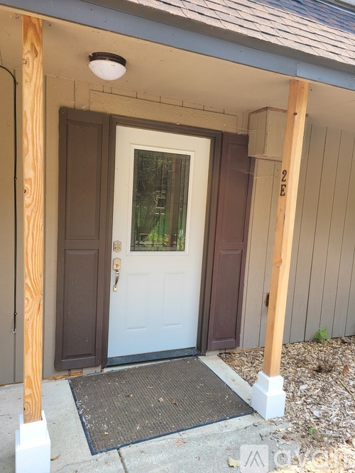A white door is flanked by two wooden posts.