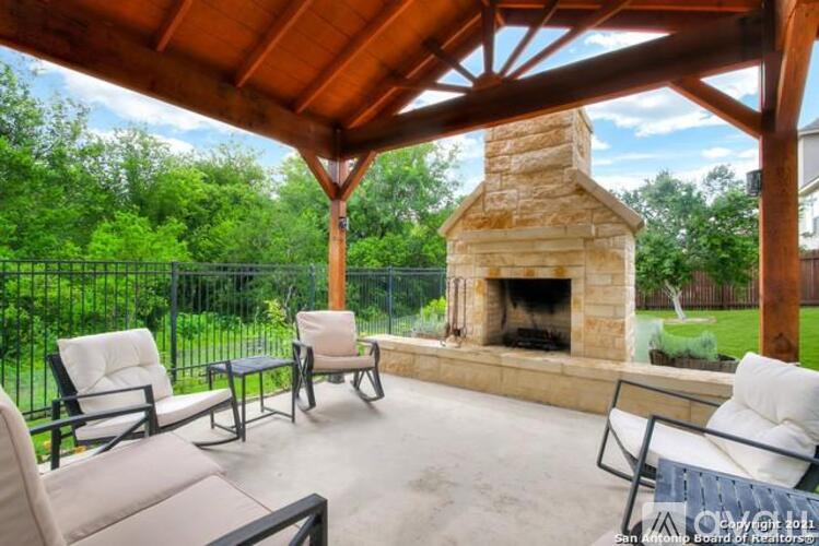 A patio with a fireplace and chairs under a wooden roof.