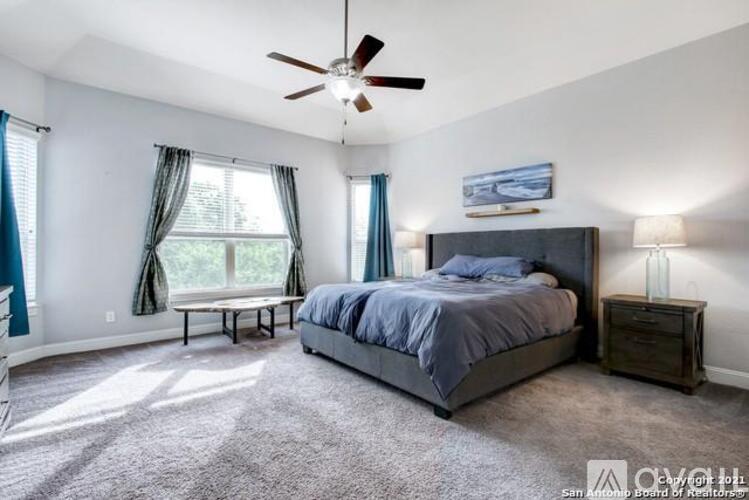 A bedroom with a bed, a ceiling fan, and a window with curtains.