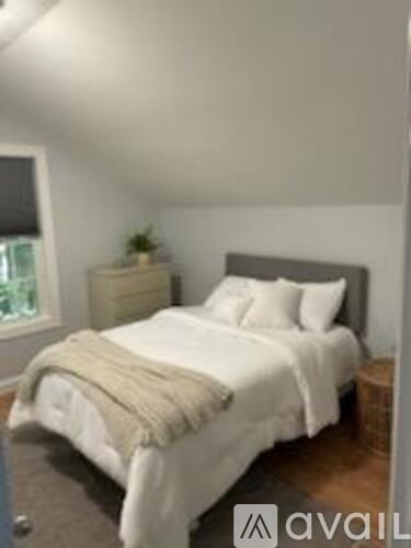A bedroom with a bed, nightstand, and window.