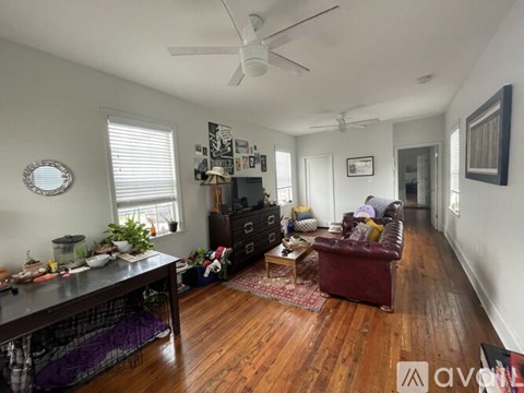 A living room with a red couch and a wooden floor.