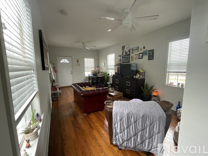 A living room with a couch, a television, and a ceiling fan.