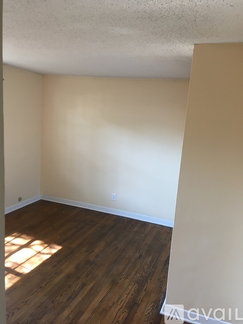 A room with wooden flooring and white walls.