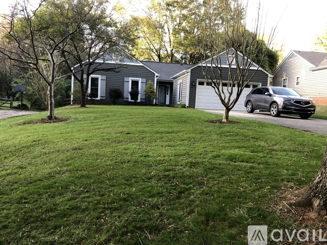 A house with a grey roof and a tree in front of it.