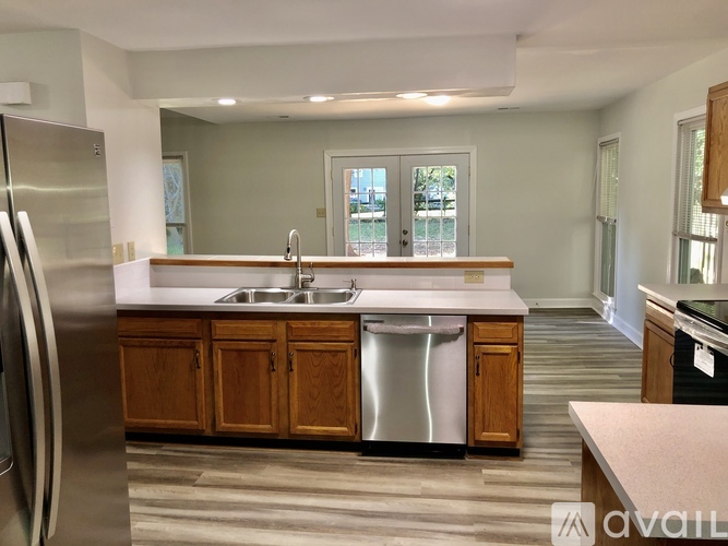 A kitchen with a stainless steel refrigerator and wooden cabinets.
