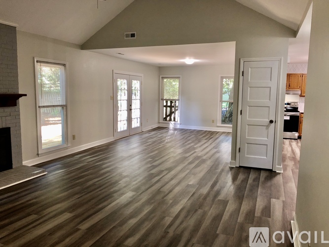 A spacious room with wood flooring and a fireplace on the left side.