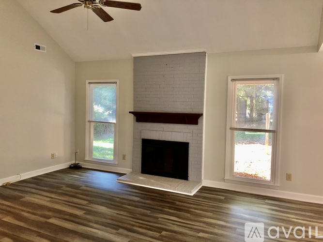 A living room with a fireplace and a ceiling fan.