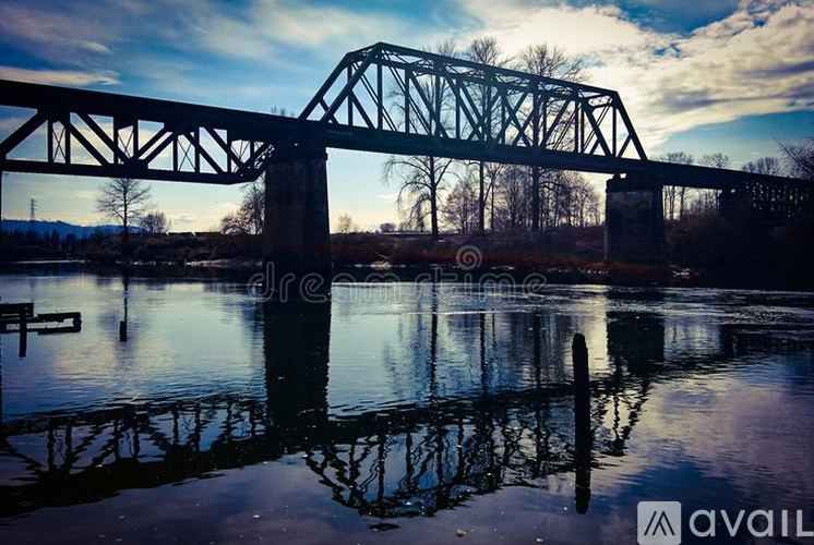 A bridge spans over a calm body of water with trees in the background.
