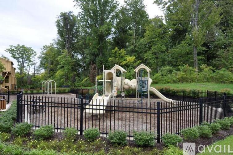 A playground with a slide and a climbing structure surrounded by a black fence.