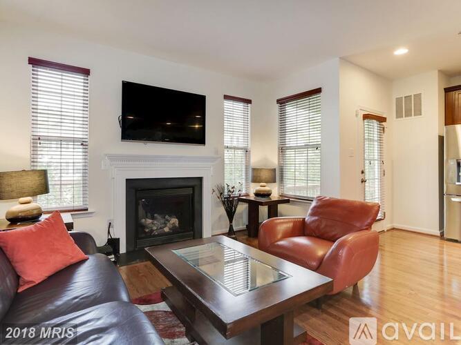 A living room with a fireplace and a television mounted above it.