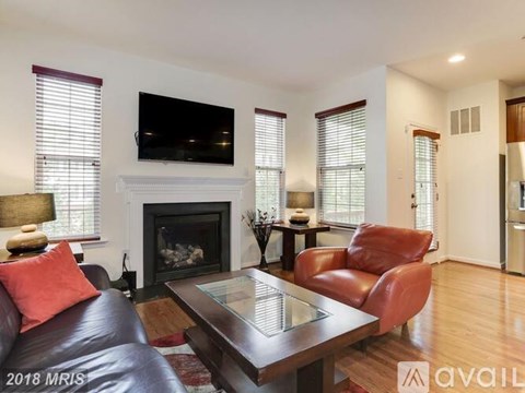 A living room with a fireplace and a television mounted above it.