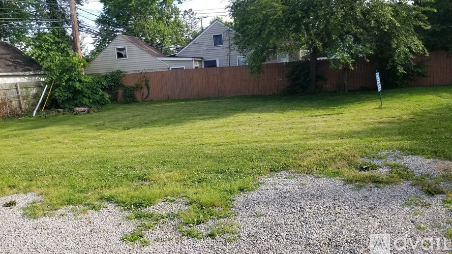 A backyard with a gravel area and a green lawn.