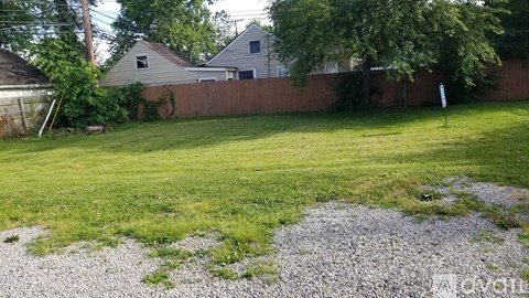 A backyard with a gravel area and a green lawn.