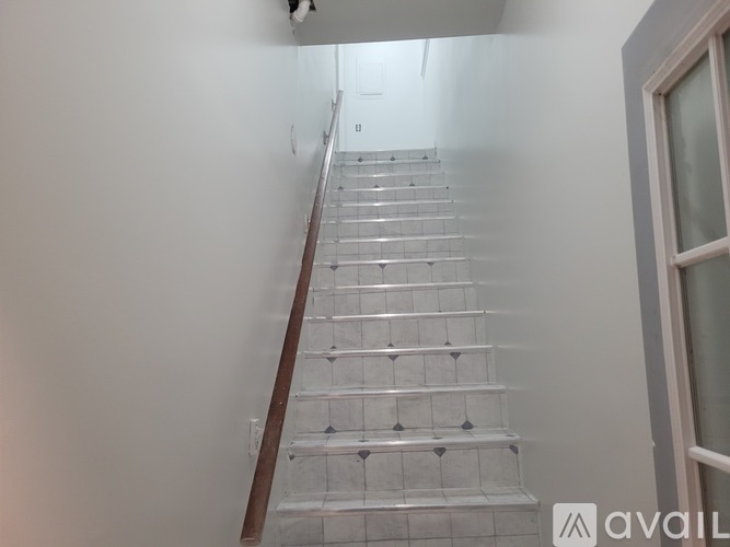 A staircase with a wooden handrail and white tiles.