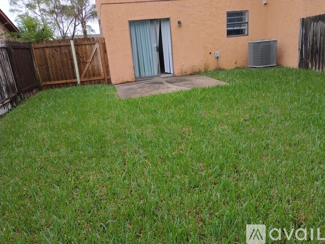 A small house with a brown fence and a green lawn.