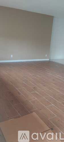 A room with wooden flooring and a wall with two switches.
