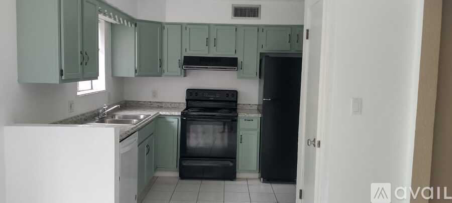 A kitchen with a black refrigerator and white countertops.