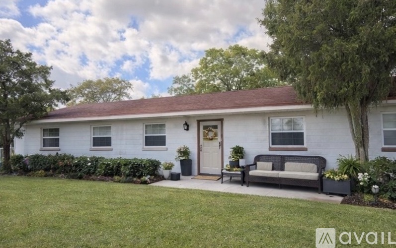 A white house with a brown roof and a front porch.