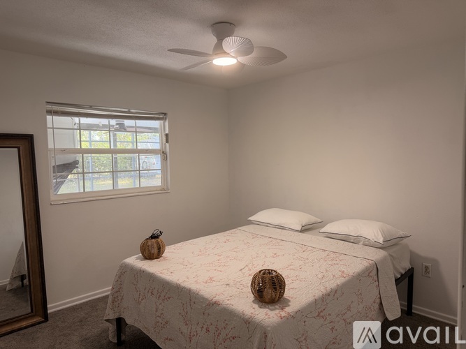 A bedroom with a bed, pillows, a ceiling fan, and a window.