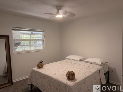 A bedroom with a bed, pillows, a ceiling fan, and a window.