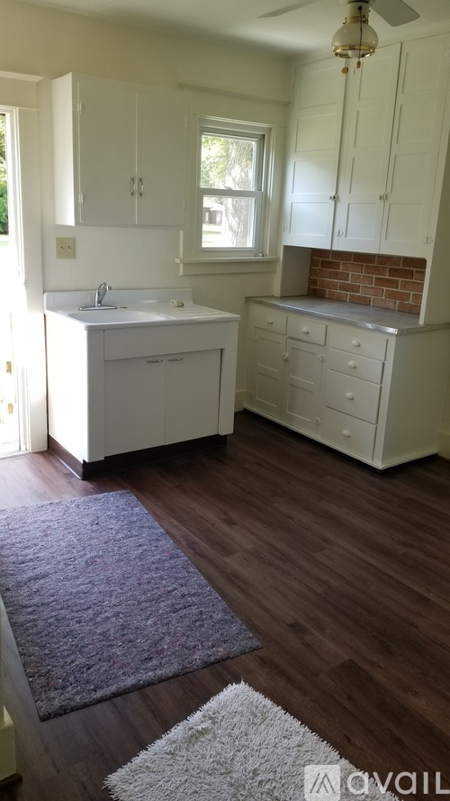 A kitchen with white cabinets and a brick backsplash.