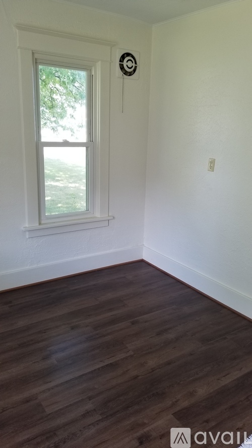 A room with a window and a smoke detector on the wall.
