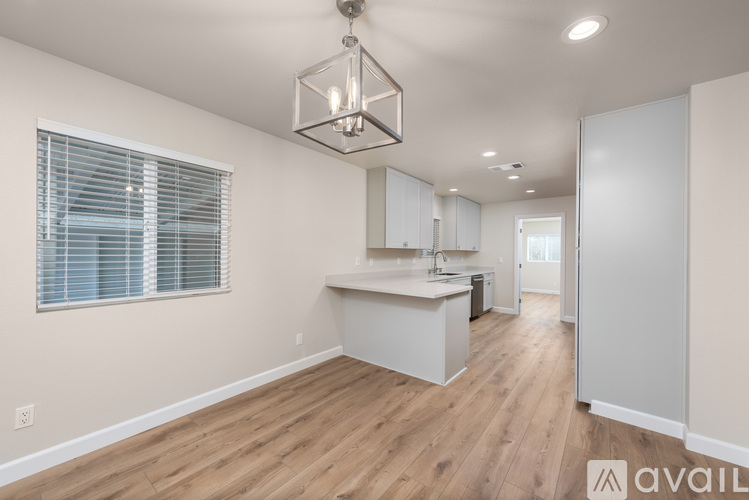 A kitchen with white cabinets and a wooden floor.