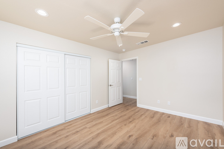 A room with a ceiling fan and two doors.