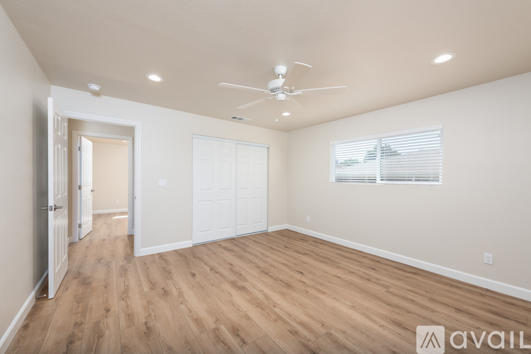 A spacious room with a ceiling fan and wooden flooring.