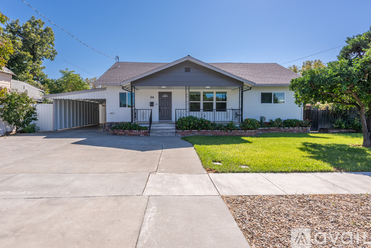 A house with a grey roof and white walls has a driveway in front.